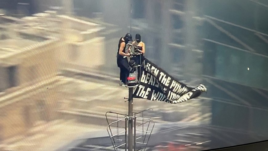 Two people climb to the top of Empire State Building with massive banner